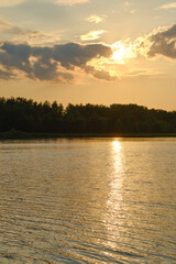 Hot day by the lake as the sun sets over the calm waters and trees in the background