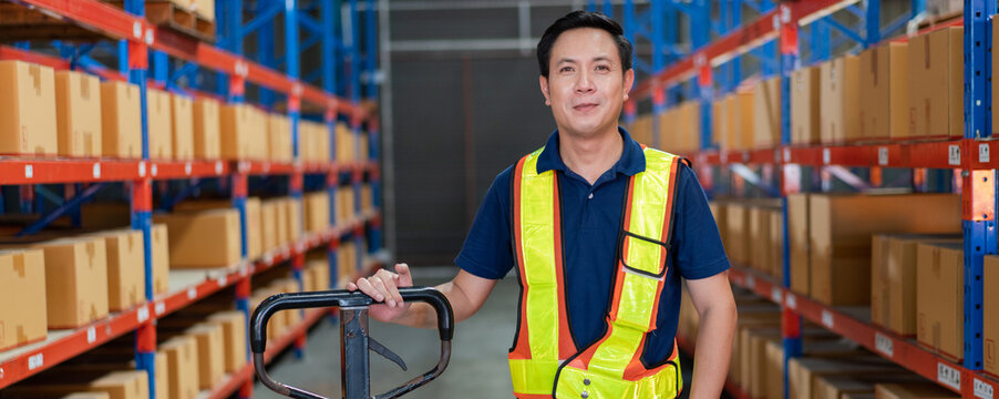 Smiling Asian warehouse worker with trolley in safety gear. Represents dedicated logistics professional and efficient industrial operations - Powered by Adobe
