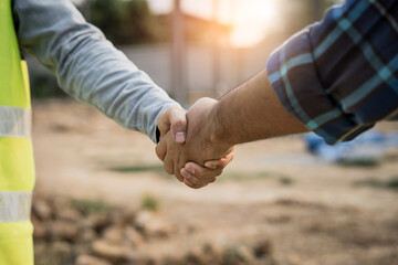 construction worker and contractor. Client shaking hands with team builder in the factory construction site.