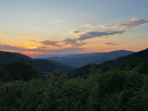 Sunset over the Mountains in Castagno d&rsquo;Andrea &ndash; Panoramic View of the Tuscan Hills with a Glowing Red Sky as the Sun Sets Behind the Peaks, Capturing the Tranquil Beauty of the Landscape