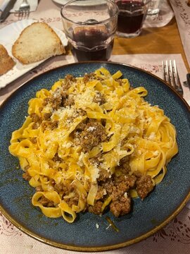 Traditional Tuscan Meal in Il Mugello &ndash; Plate of Pappardelle al Rag&ugrave; di Cinghiale with a Glass of Red Wine, Celebrating Local Flavors in a Warm and Authentic Setting