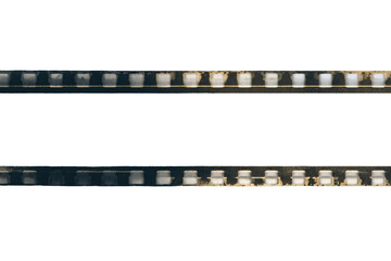 Obraz premium Two parallel horizontal rows of film strips, faded and distressed, against a black background. Color variations and imperfections are visible on the strips