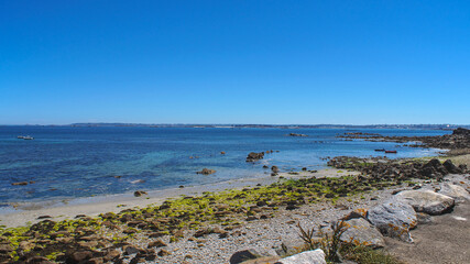 Bay near Roscoff, Brittany, France &ndash; view of water and coastline under a clear blue sky.