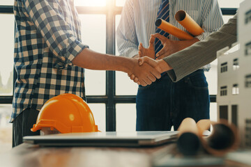 Construction worker shaking hands with businesswoman in office after closing deal for new building project