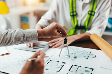 Team of architects using compass and set square working together on construction blueprint at office desk © Crystal