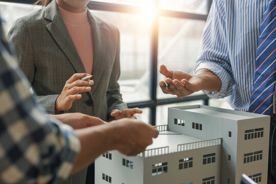 Architects and engineers discussing and planning a building project using a scale model in a bright office