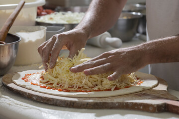 Chef pizzaiolo prepara uma pizza colocando queijo mussarela na massa da pizza