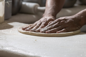 Chef pizzaiolo prepara uma pizza abrindo a massa com as mãos
