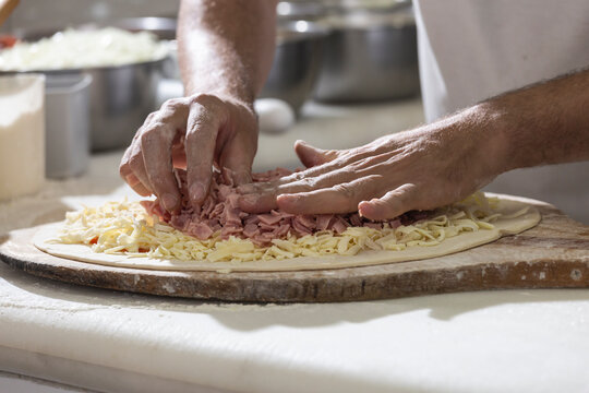 Mão de um Chef pizzaiolo preparando uma pizza - Powered by Adobe