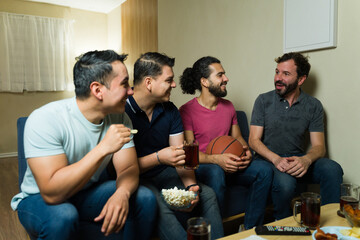 Group of male friends watching basketball game at home