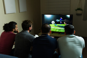 Rear view of friends watching football match on tv at home