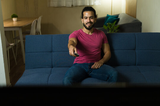 Hispanic man relaxing on sofa and watching tv