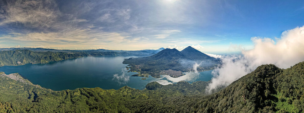 Aerial panoramic view of Lake Atitl&aacute;n and San Pedro in Guatemala with volcanic mountains, lush green landscape, and dramatic sky over Central America