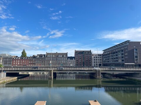 View of the Sphinxkwartier in Maastricht &ndash; Clear Blue Sky Over Water, Dutch-Style Houses and a Bridge with Cars, Capturing the Urban Charm of the Netherlands Along the River