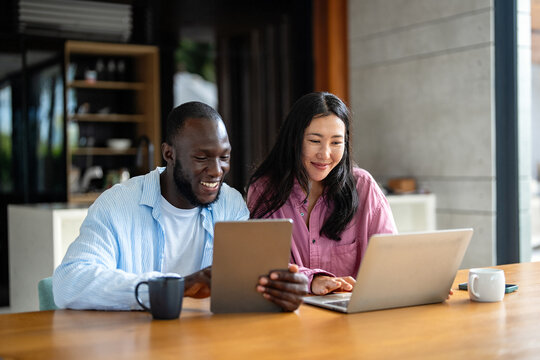 Happy multiethnic diverse couple, people using digital laptop for online shopping or payment.