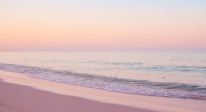 Soft pastel sunset over a calm ocean and sandy beach