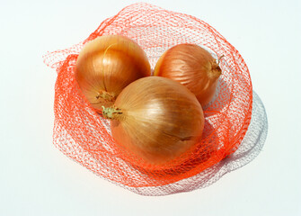 Three yellow onions nessled inside of an orange mesh bag.