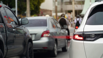 Rear side of white car with turn on brake light. Red light speed on tail light of car. Condition of busy cars on urban roads in Thailand. Cars lined up from traffic lights.
