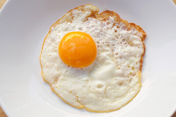 Fried egg on white dish close up