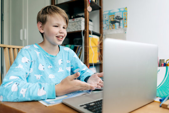 A teenage boy uses a laptop for an online lesson with a tutor.