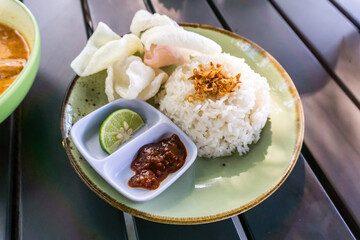 A delicious, complete meal of Minapadi chicken curry with rice, crackers, and chili sauce