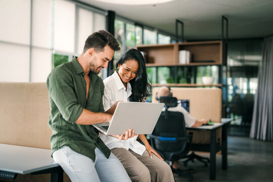 Two happy diverse multiethnic business team people working, talking in corporate office