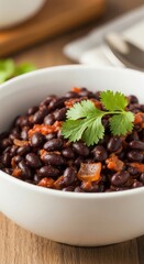 Obraz premium Close up of a bowl of cooked black beans with a fresh cilantro garnish