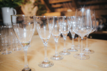 A row of sparkling clean wine glasses lined up on a wooden surface, set in a rustic indoor setting, ready for a celebration or formal event.