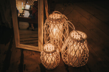 Three white wicker lanterns with glowing candles create a warm, cozy ambiance next to a decorative...
