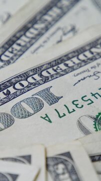 Vertical video. Scattered Hundred Dollar Notes Rotate Gently, Portraying Concepts Of Financial Planning, Revenue Streams, Cash Rotation, And Investment Stability.