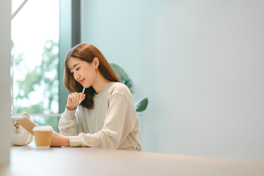 Adult asian business woman using digital tablet working and relax at cafe sitting near window