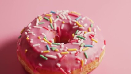 Sprinklecovered donut with pink frosting suitable for bakery shops, dessert promotions, food blogs, or social media posts with sweet themes.