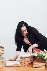 teacher with stacks of books on table