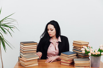 teacher with stacks of books on table