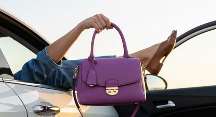 Purple handbag held by female hand resting in car