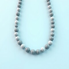 Obraz premium Close up of a delicate necklace made of small grey stone beads on a light blue background