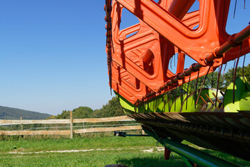 The close-up of a combine harvester reveals its detailed components against a bright blue sky.