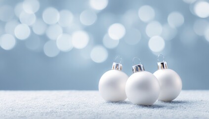 Three white christmas ornaments on a bed of simulated snow.