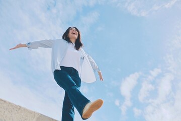 happy young asian woman jumping in the air under the blue sky background.