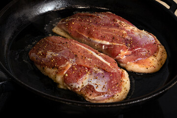 two duck breasts are fried in a pan, seasoned with salt and a mixture of peppers