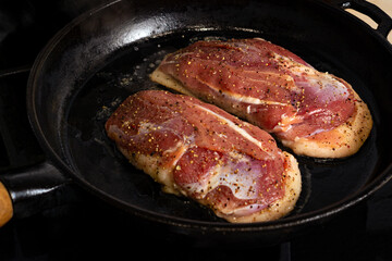 two duck breasts are fried in a pan, seasoned with salt and a mixture of peppers