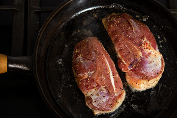 two duck breasts are fried in a pan, seasoned with salt and a mixture of peppers
