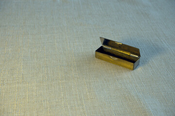 Small open bronze jewelry box placed on a table, showcasing its interior.