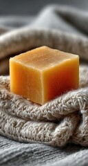 A close-up of a block of light orange-yellow soap resting on a textured beige towel