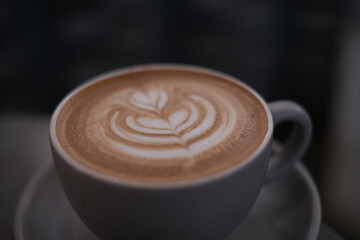 Close up white coffee cup with heart shape latte art on the table in a cafe