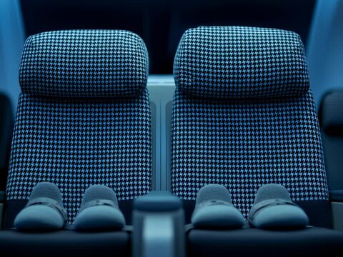 Two spacious airline seats with stylish houndstooth pattern are accompanied by soft slippers, inviting passengers to relax in comfort during a nighttime journey.