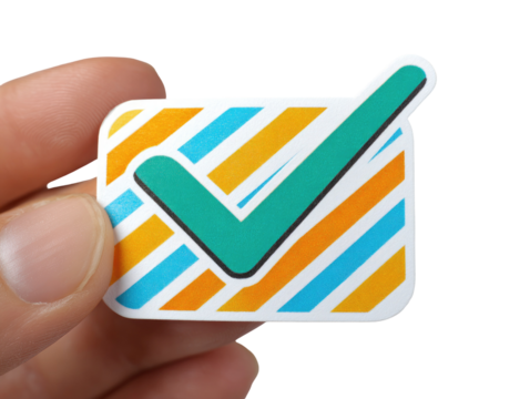 A hand holds a small, square sticker. The sticker features a teal checkmark inside a light orange and teal striped rectangular frame