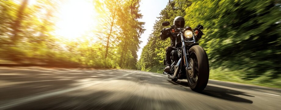 The motorcycle rider speeding down a sunlit tree-lined road at high speed