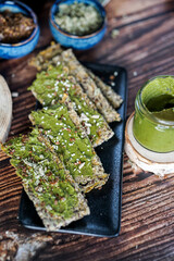 Woman hands spreading home made basil pesto on home baked gluten free bread