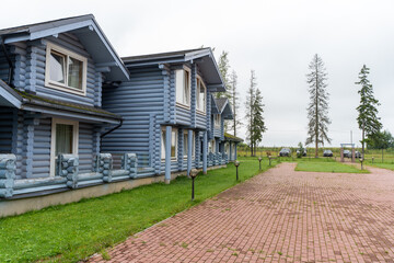 Modern log house, wooden holiday home, blue wooden house with big windows, balcony and veranda, green grass. Eco hotel